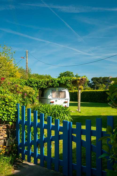 Photo d'une caravane dans un jardin verdoyant.